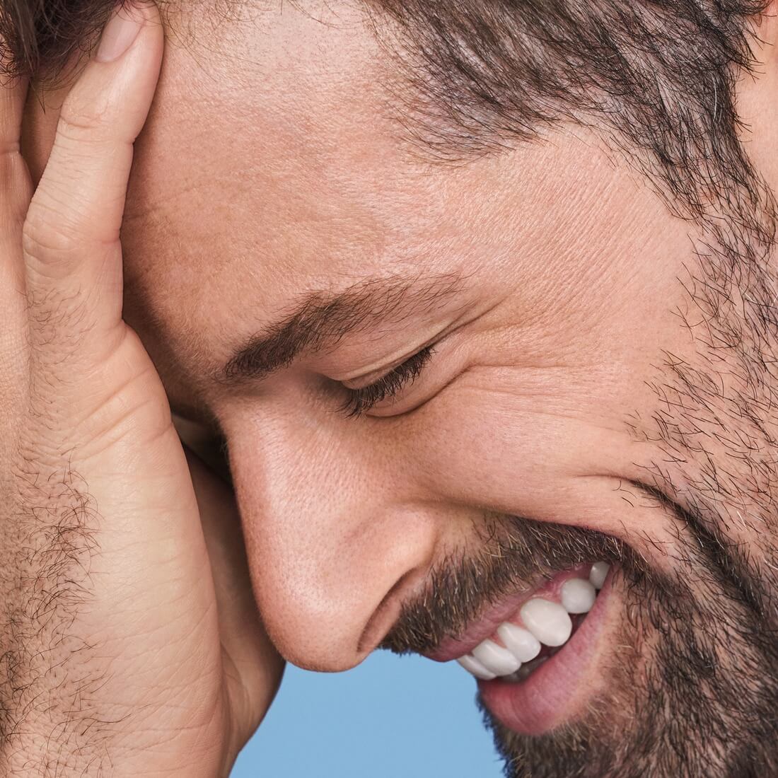 Closeup of man with full beard smiling with eyes closed