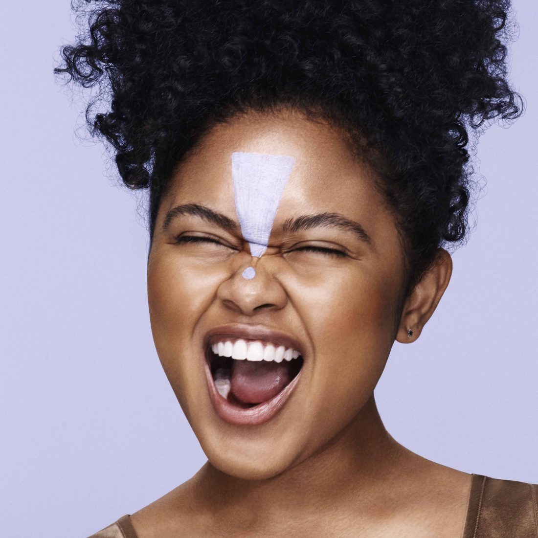 Young woman with dark skin with Unblemish Clarifying Mask applied to her forehead