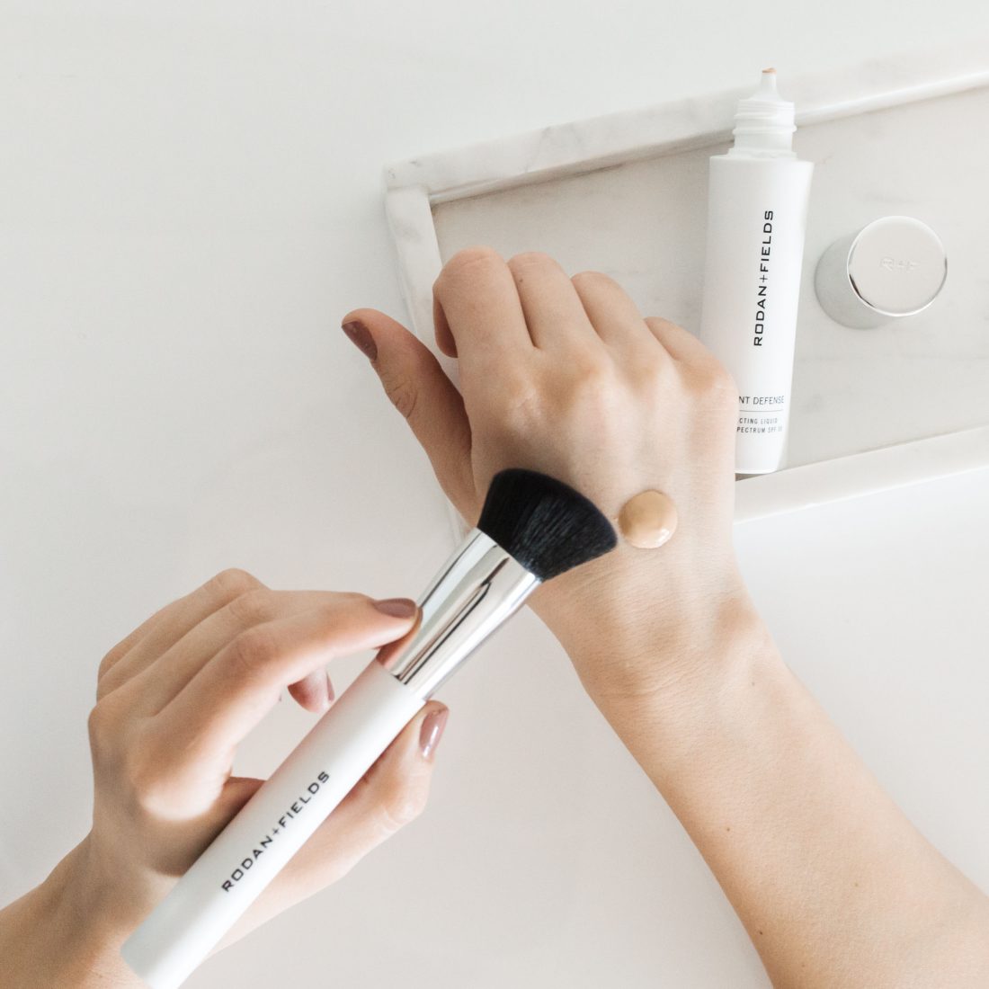 Radiant Defense Perfecting Liquid applied to the back of the hand via the included brush