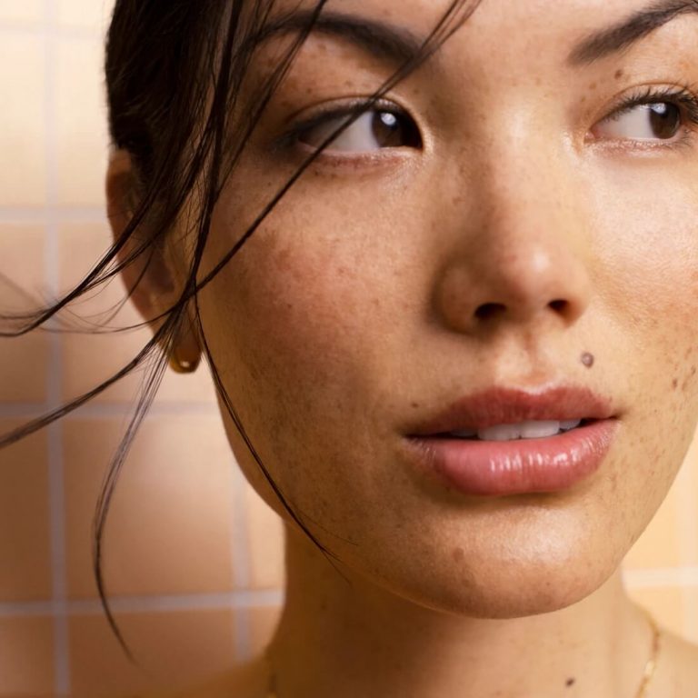 Closeup of young woman with freckles in a tiled bathroom