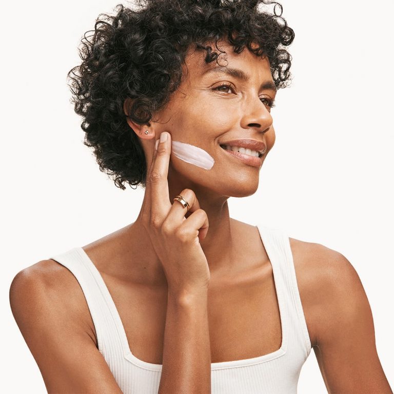 Woman applying Rodan + Fields anti-aging cream to her face