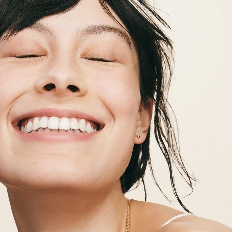 Woman without makeup smiling with eyes closed