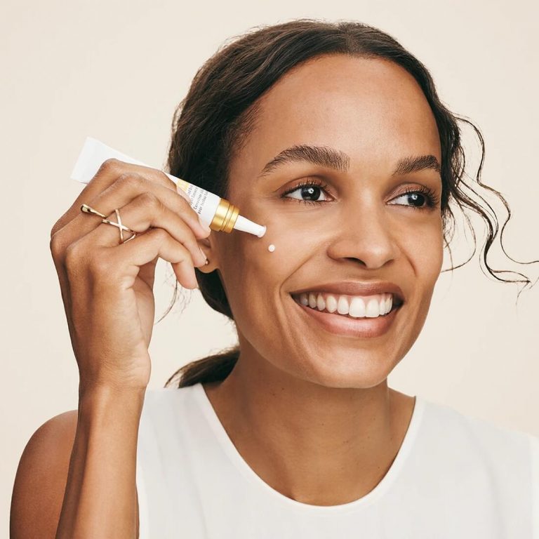 Woman with dark skin applying Rodan + Fields Reverse Dark Spot Corrector to her face