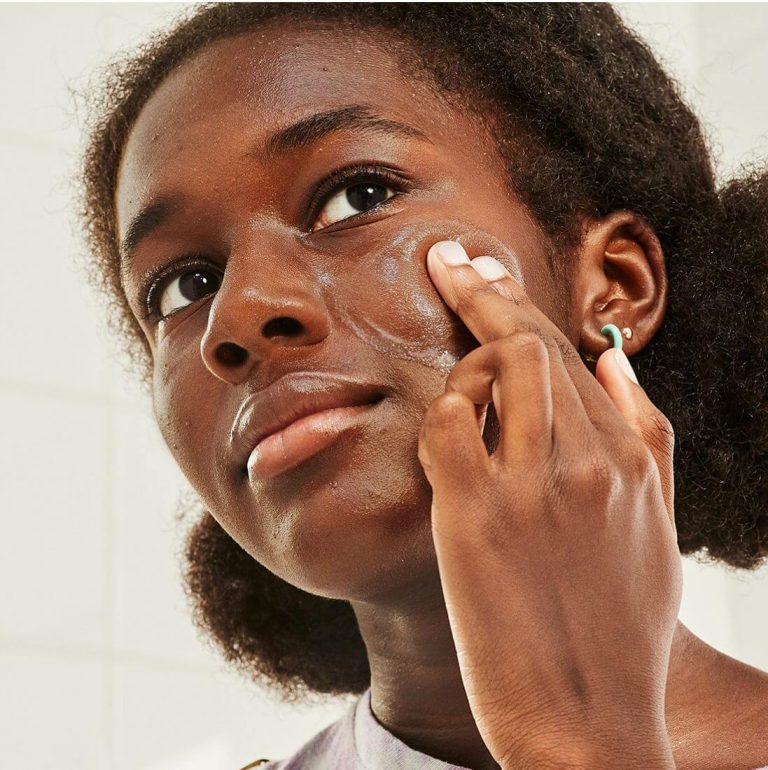 Young woman applying acne product to her face