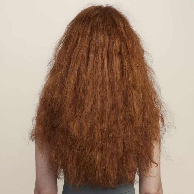 Young woman shown from the back with thick wavy frizzy hair