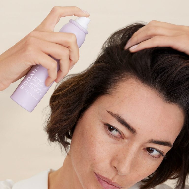 Woman with dark hair applying Rodan + Fields Refresh+ Dry Shampoo