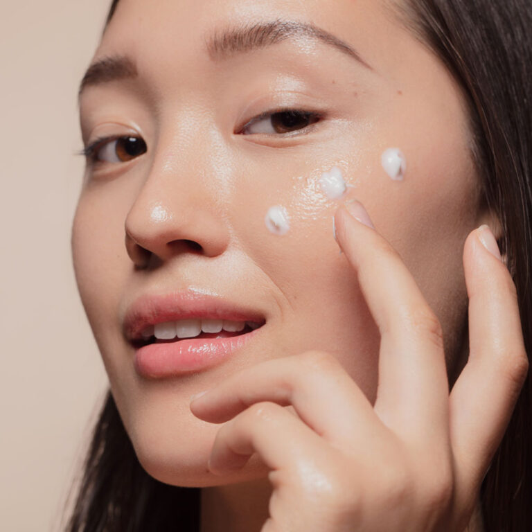 Young woman showing glass skin with product applied to face