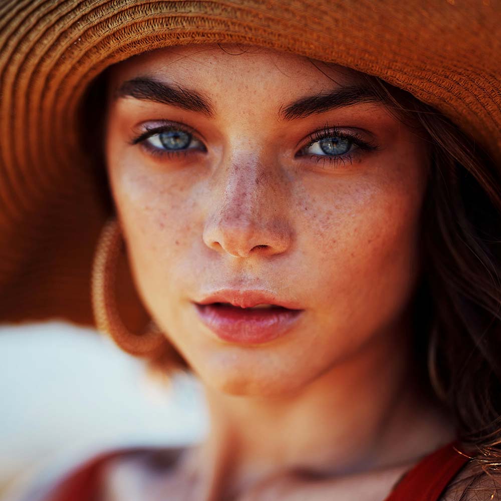 Young woman with freckles wearing a sun hat. Photo by Ben Scott.