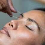 Woman with eyes closed having eyebrows threaded. Photo by Rune Enstad.
