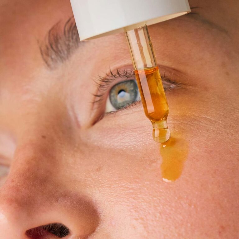 Closeup of vitamin C serum applied to the face via dropper.